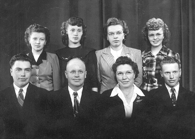 photo: Family portrait of Norman Rost family: back row - Alice, Rosie, Reva and Irene. Front row - Merrill, Norman, Bertha and Mervin.
